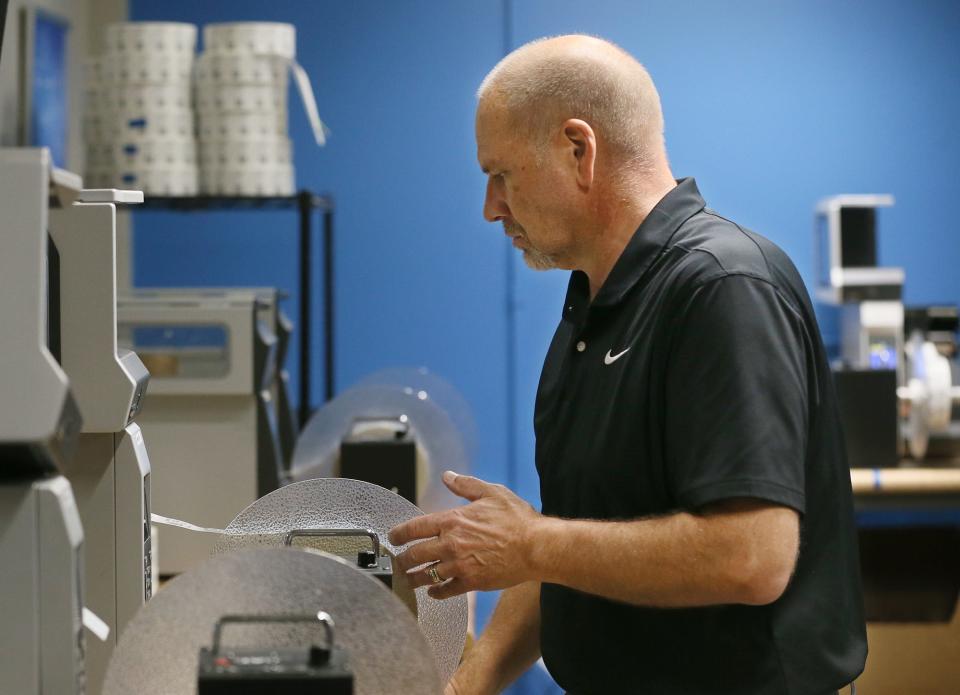 Bob Groh, a production assistant at Surgere, check on a roll encoded RFID tags at the facility in Green.