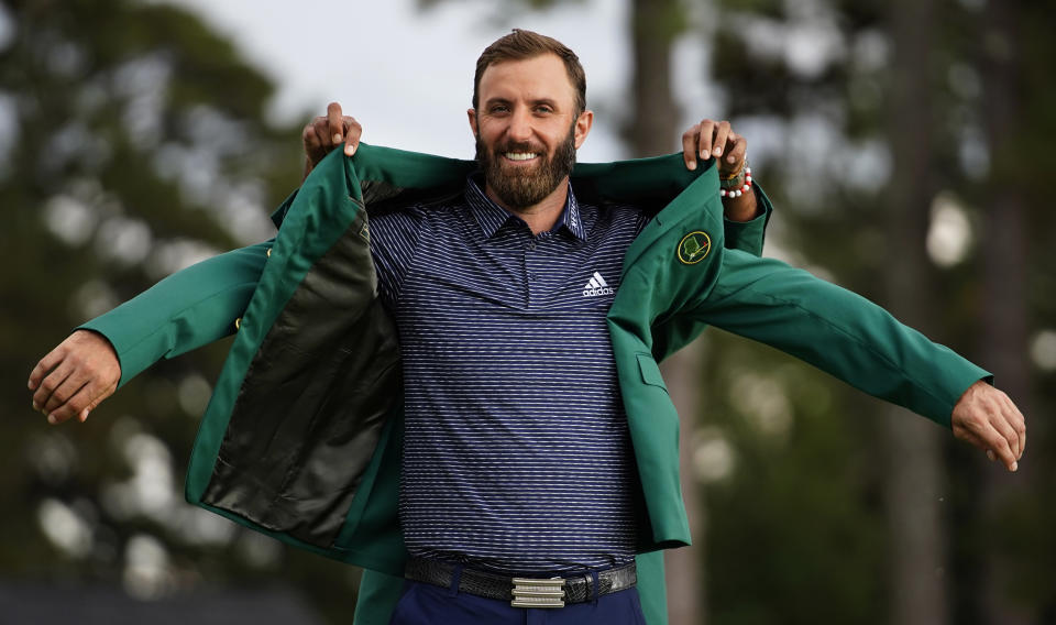 FILE - Tiger Woods helps Masters champion Dustin Johnson with his green jacket after his victory at the Masters golf tournament in Augusta, Ga., in this Nov. 15, 2020, file photo. No one else ever won the Masters and then didn't play in another tournament the rest of the year. No other Masters champion was allowed to keep his green jacket for only five months before it was time to try to win it again. Then again, no one ever played the Masters in November. (AP Photo/Matt Slocum, File)