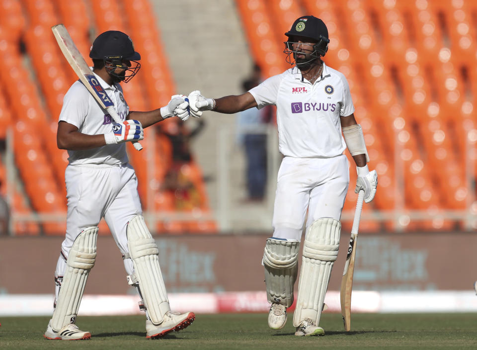 India's Rohit Sharma, left, fist bumps teammate Cheteshwar Pujara as they walk off the field at the end of first day's play of fourth cricket test match between India and England at Narendra Modi Stadium in Ahmedabad, India, Thursday, March 4, 2021. (AP Photo/Aijaz Rahi)