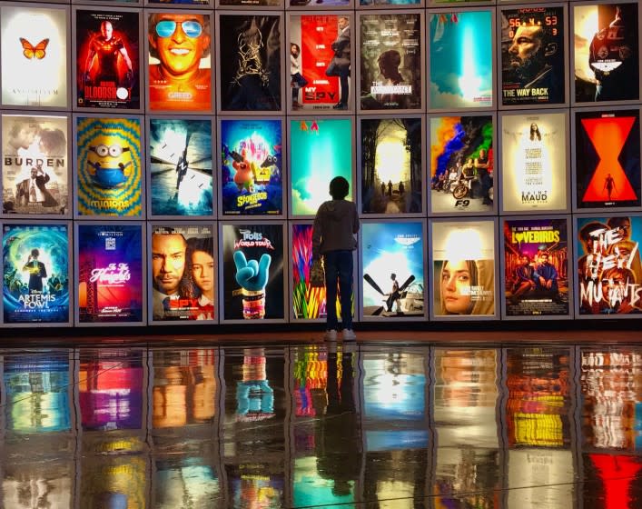 MANHATTAN BEAC CA. MARCH 12, 2020 - A child looks at movie posters inside the lobby of the Arclight movie theater In Manhattan Beach, Ca., March 12,2020. The industry is taking big losses as coronavirus spreads, with blockbusters like the latest James Bond movie and Fast and the Furios installments, being postponed indefinitely. (Jay L. Clendenin / Los Angeles Times)