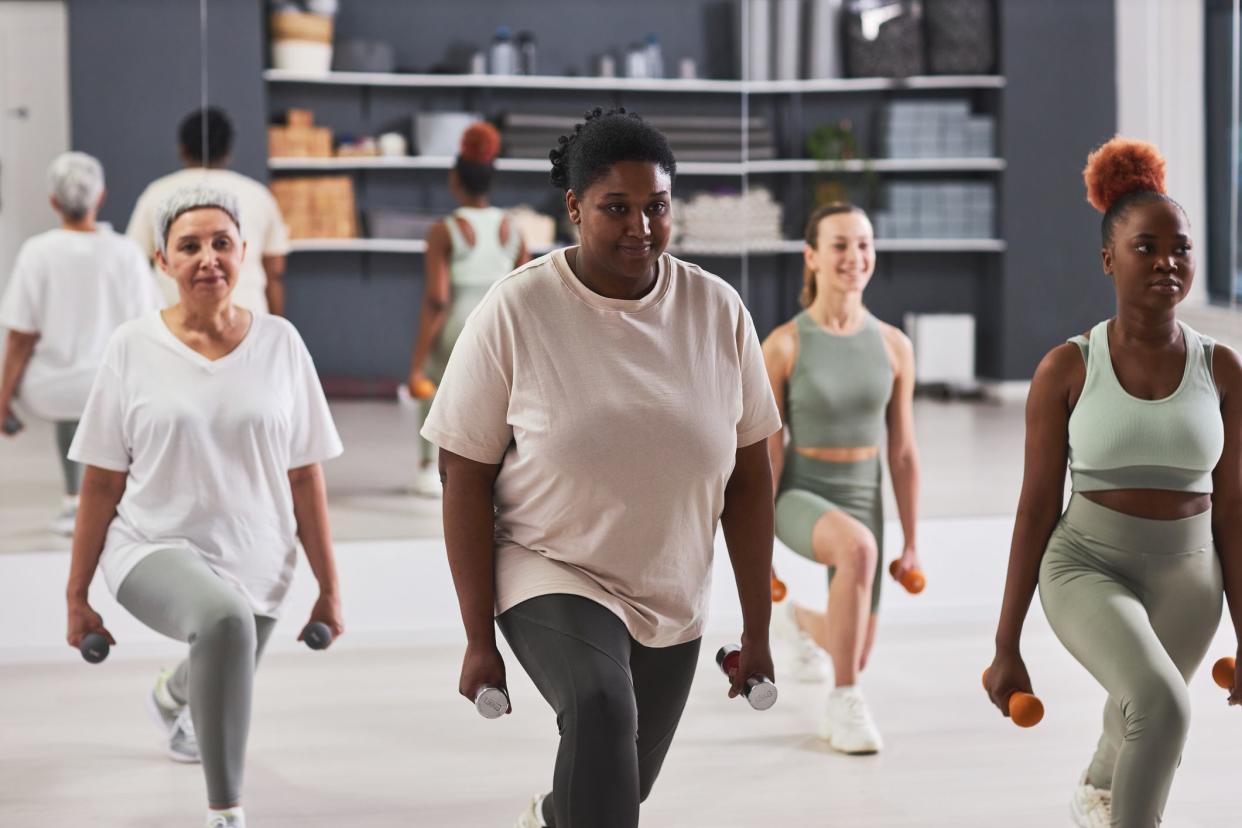 Group of women exercising with dumbbells together during sport training in gym