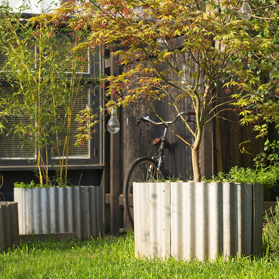 garden grass with large metal planters and small trees