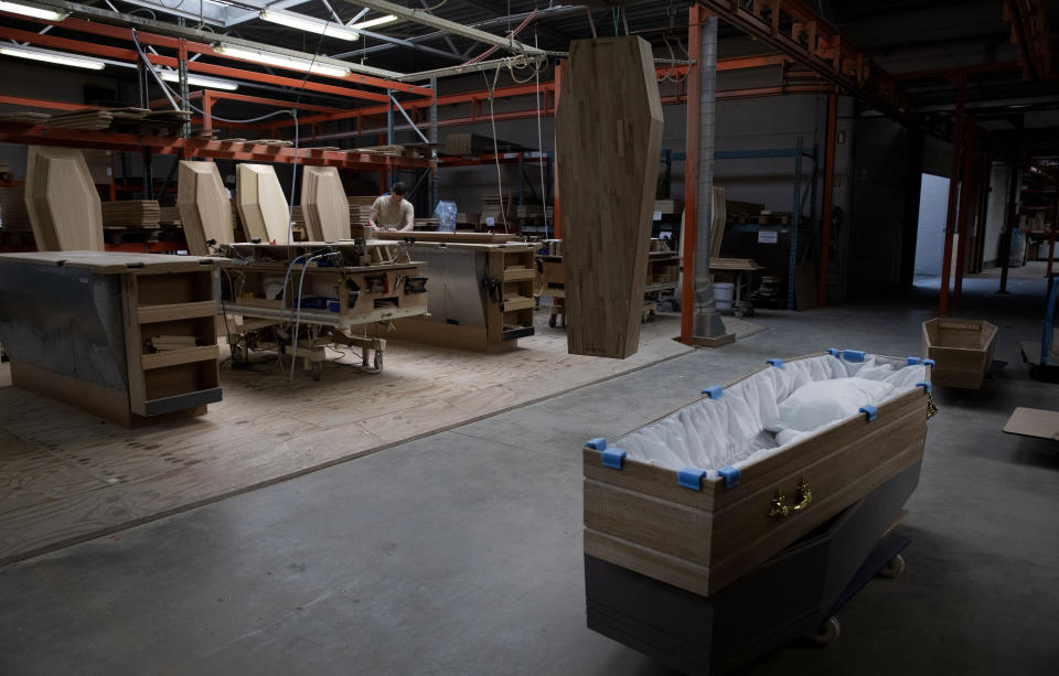 FILE - In this Thursday, April 9, 2020 file photo, an employee at a woodworking station works on a section of a casket at the production warehouse of Aninco in Peer, Belgium. After the European Union passed the death toll of half a million citizens lost to the coronavirus on Wednesday, Feb. 10, 2021, the EU Commission chief said that stalling rollout of the vaccines could be partly blamed on the bloc being over-optimistic, over-confident and plainly "too late." (AP Photo/Virginia Mayo, File)
