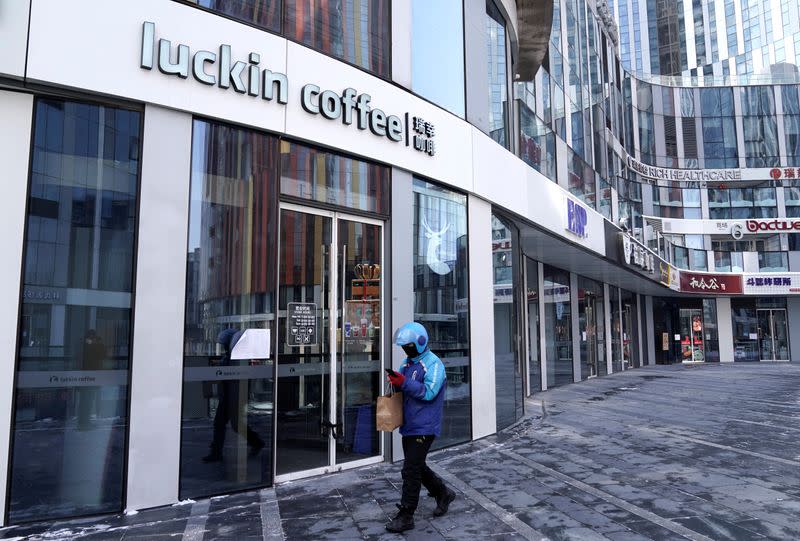 FILE PHOTO: A deliveryman walks past a closed Luckin Coffee store at Sanlitun in Beijing