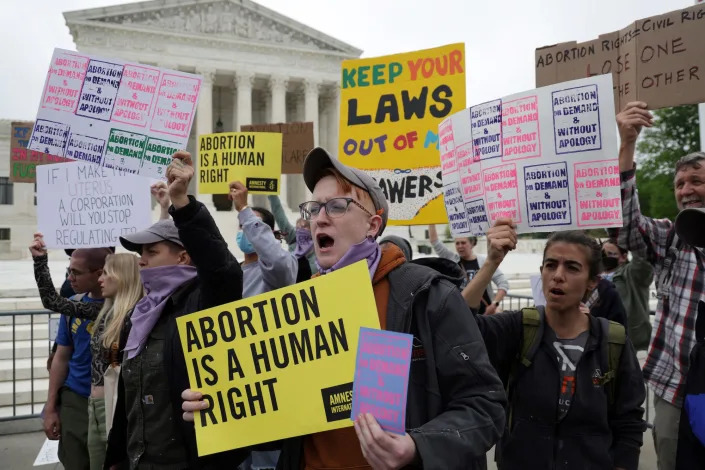 A group of abortion rights activists, some hoisting homemade signs aloft that read &quot;Abortion is a human right.&quot; protest the looming reversal of Roe v. Wade on the steps of the Supreme Court.