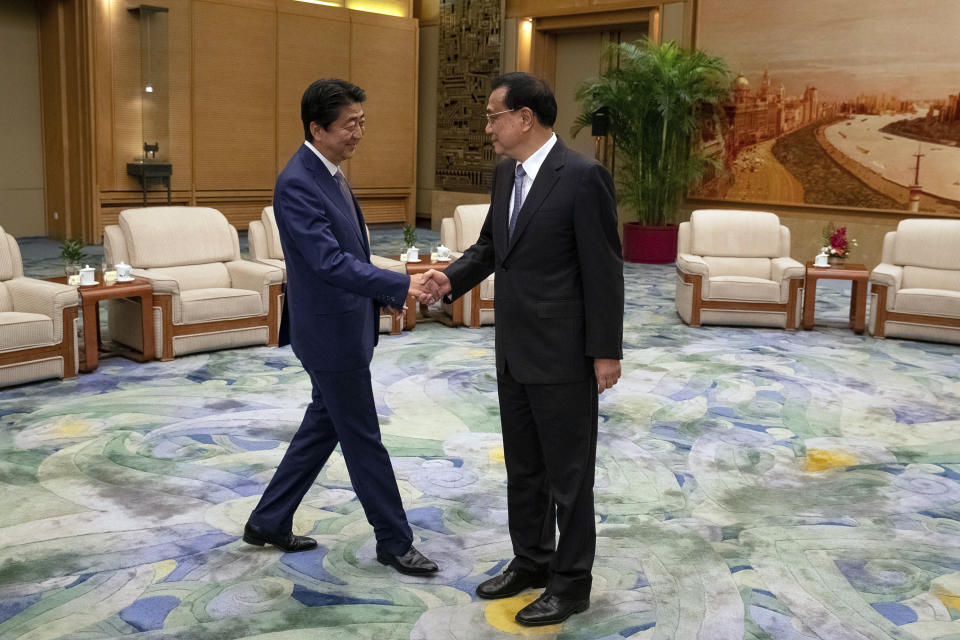 Chinese Premier Li Keqiang, right, and Japanese Prime Minister Shinzo Abe shake hands during their meeting at the Great Hall of the People in Beijing, Thursday, Oct. 25, 2018. Abe arrived in Beijing on Thursday as both countries try to repair ties that have been riven by disputes over territory, military expansion in the Pacific and World War II history. (Roman Pilipey/Pool Photo via AP)