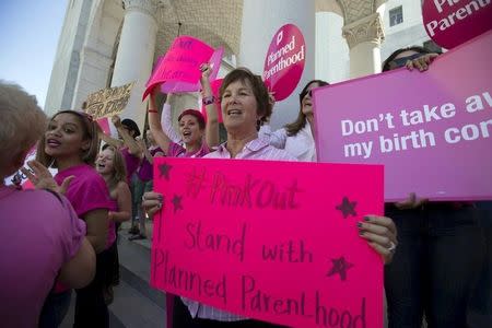 Activists hold signs as they rally in support of Planned Parenthood on "National Pink Out Day" on the steps of City Hall in Los Angeles, California September 29, 2015. REUTERS/Mario Anzuoni