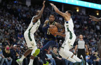 Denver Nuggets guard Monte Morris (11) drives to the basket against Milwaukee Bucks forward Khris Middleton (22) and guard George Hill (3) during the second quarter of an NBA basketball game Friday, Nov. 26, 2021, in Denver. (AP Photo/Jack Dempsey)