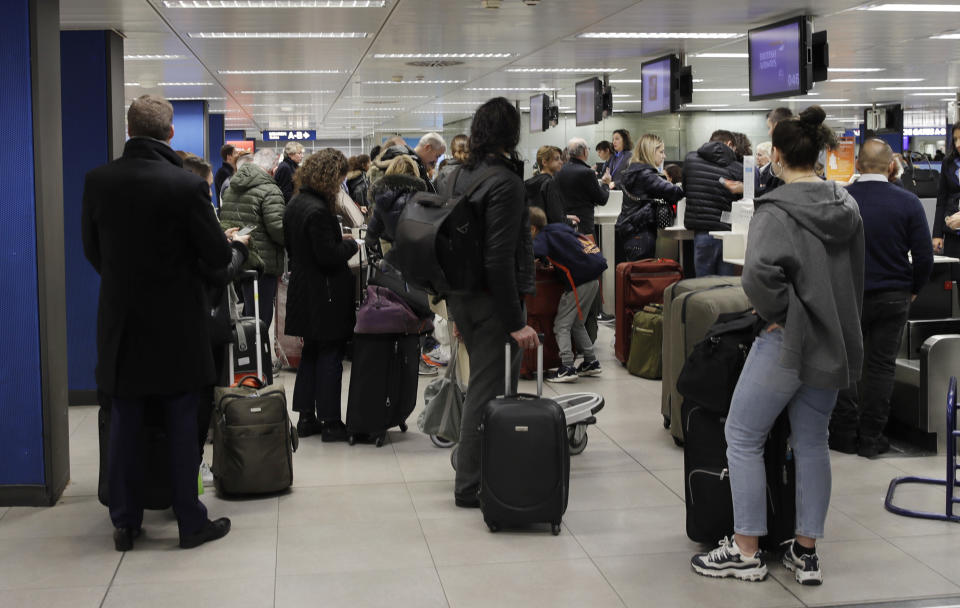 People wait at the check-in area of the Linate airport in Milan, Italy, after flights were cancelled or rescheduled as a consequence of London's Gatwick airport closure, Thursday, Dec. 20, 2018. London's Gatwick Airport remained shut during the busy holiday period Thursday while police and airport officials investigate reports that drones were flying in the area of the airfield. (AP Photo/Luca Bruno)