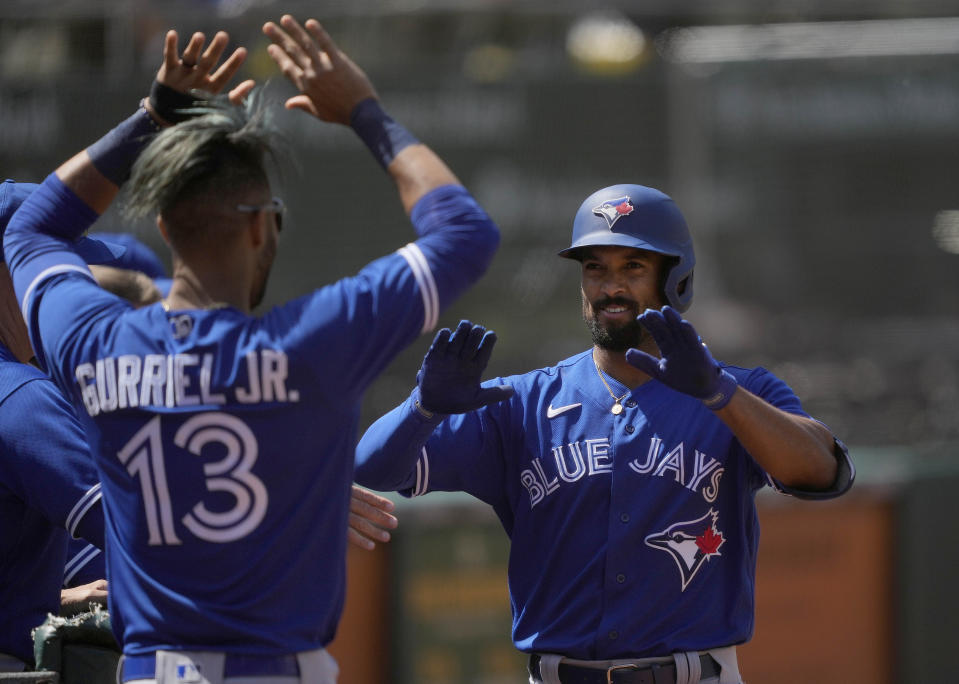 Toronto Blue Jays' Marcus Semien, right, celebrates with Lourdes Gurriel Jr. (13) after hitting a solo home run against the Oakland Athletics during the seventh inning of a baseball game in Oakland, Calif., Thursday, May 6, 2021. (AP Photo/Tony Avelar)