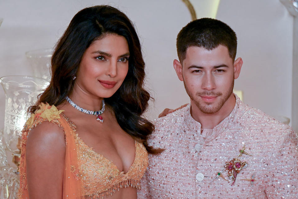 Emeralds and jewelry, Bollywood actress Priyanka Chopra Jonas (L) and her husband, American singer-songwriter and actor Nick Jonas (R), pose for photos as they arrive for the wedding ceremony of Anant Ambani, the son of billionaire and Chairman of Reliance Industries Mukesh Ambani, and Radhika Merchant in Mumbai on July 12, 2024. Sisters Kim and Khloe Kardashian were among the global stars spotted in India on July 12 as they attended a lavish three-day wedding ceremony hosted by Asia's richest man Mukesh Ambani. (Photo by Punit PARANJPE / AFP) (Photo by PUNIT PARANJPEPUNIT PARANJPE/AFP via Getty Images)