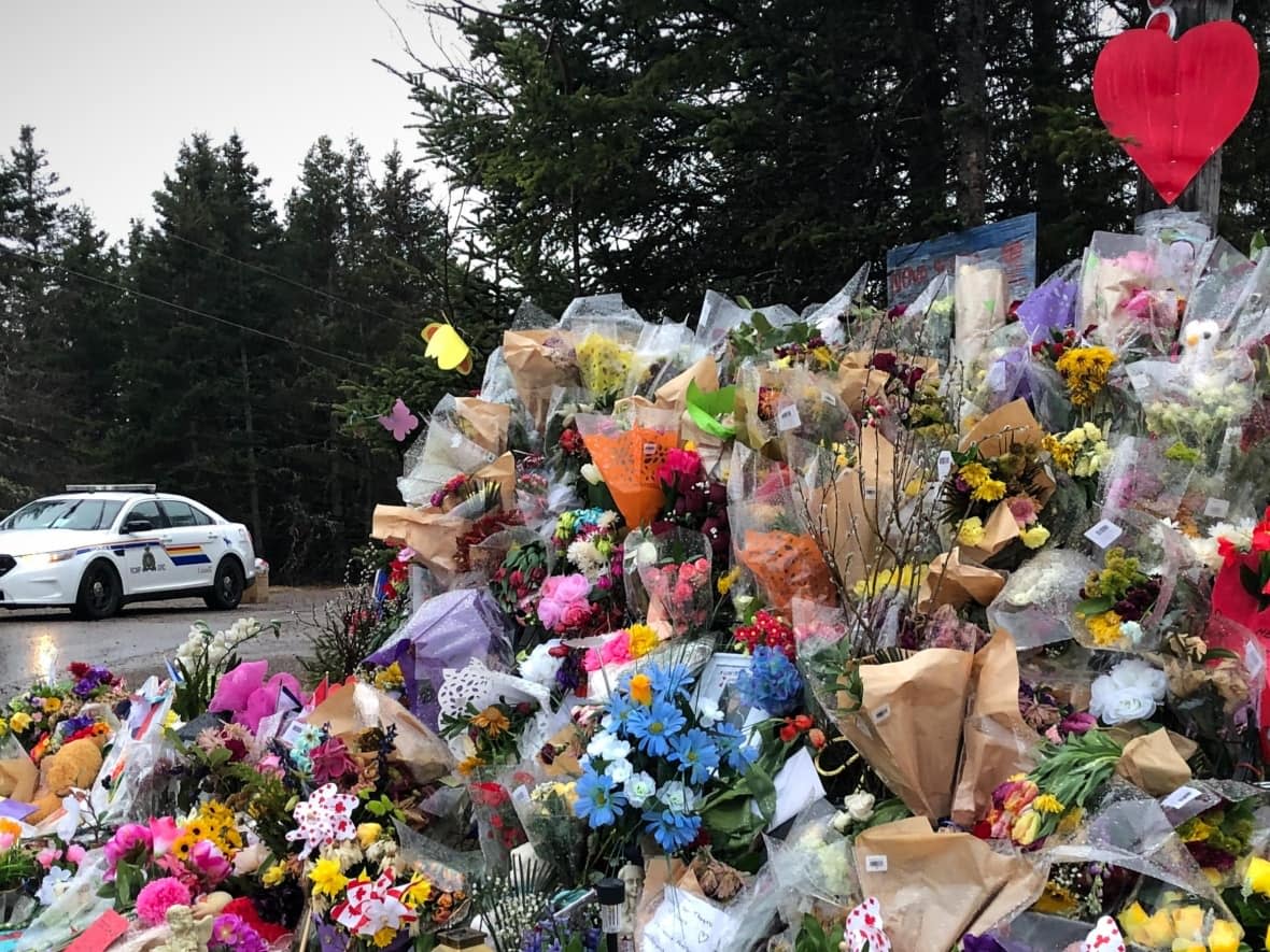 An RCMP car is seen near a memorial display in Portapique following the mass shooting in April 2020. (Brett Ruskin/ CBC - image credit)