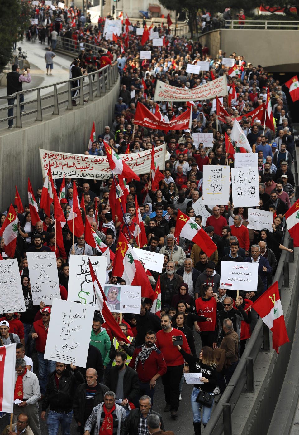 Anti-government demonstrators hold banners during a march organized by the country's communist party, in Beirut, Lebanon, Sunday, Dec. 16, 2018. Hundreds of Lebanese called for an end to a stalemate over forming a government seven months after elections. The Sunday protests were organized by the country's vibrant communist party, but drew others frustrated by the country's deepening economic and political crisis. (AP Photo/Hussein Malla)