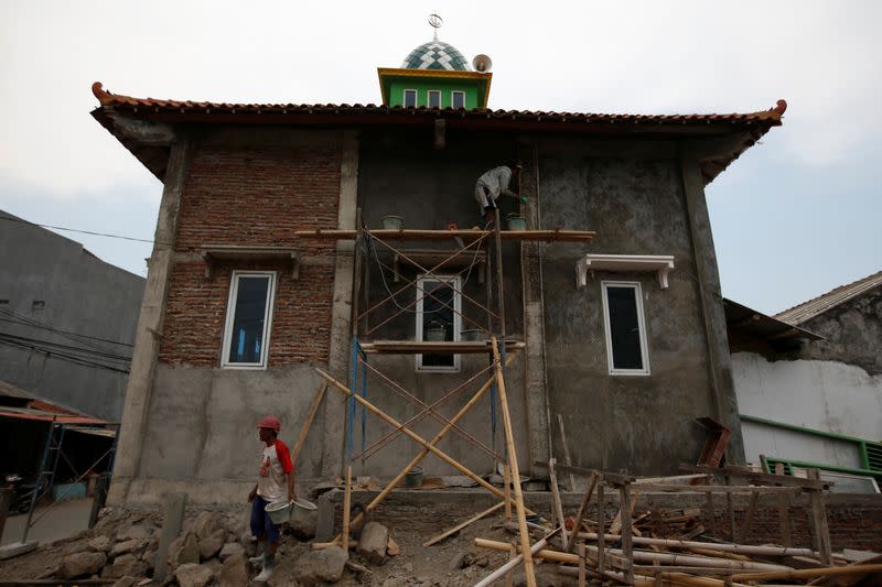 Labourers work on a mosque, renovating it to be raised due to land subsidence, at Tambakrejo village in Semarang