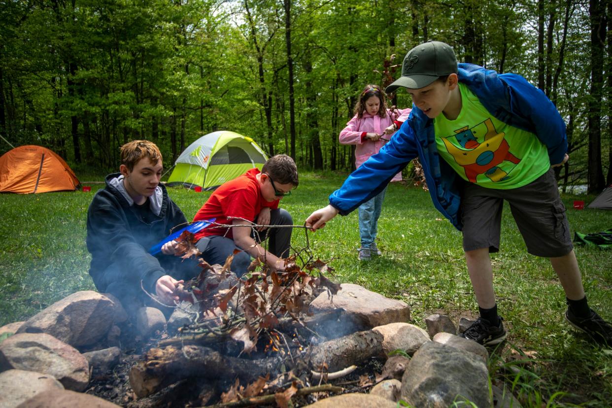 Left to right, Alexzander Burt, 16, Logan Pharris, 12, Violet Osantowske, 11, and Simon Osantowske, 11, work on building a fire at D Bar A Scout Ranch in Metamora on Saturday, May 21, 2022. The Troop 1402 camping trip was planned solely by the scouts and the parents sit on standby so scouts can practice planning, cooking, and wilderness skills.