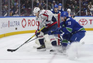 Washington Capitals' T.J. Oshie (77) is checked by Vancouver Canucks' Elias Lindholm (23) during the second period of an NHL hockey game in Vancouver, British Columbia, Saturday, March 16, 2024. (Darryl Dyck/The Canadian Press via AP)