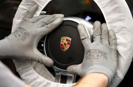 A worker assembles a steering wheel of a new Porsche 911 sports car at the Porsche factory in Stuttgart-Zuffenhausen, March 10, 2015. REUTERS/Michaela Rehle/Files