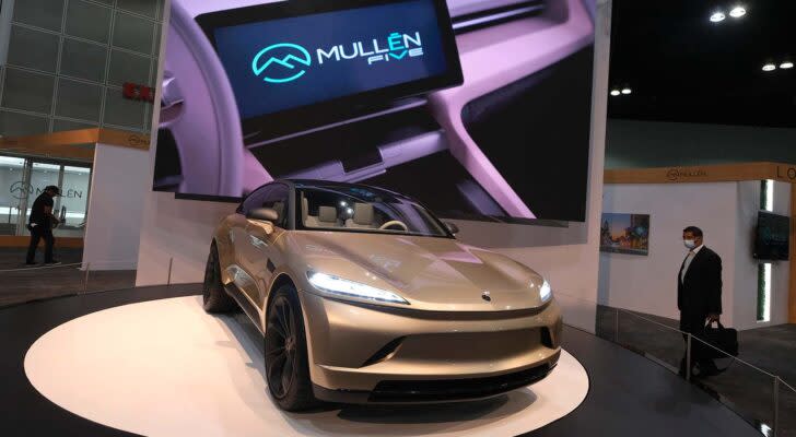 An angled shot of the Mullen (MULN) Five on display with a screen behind it.