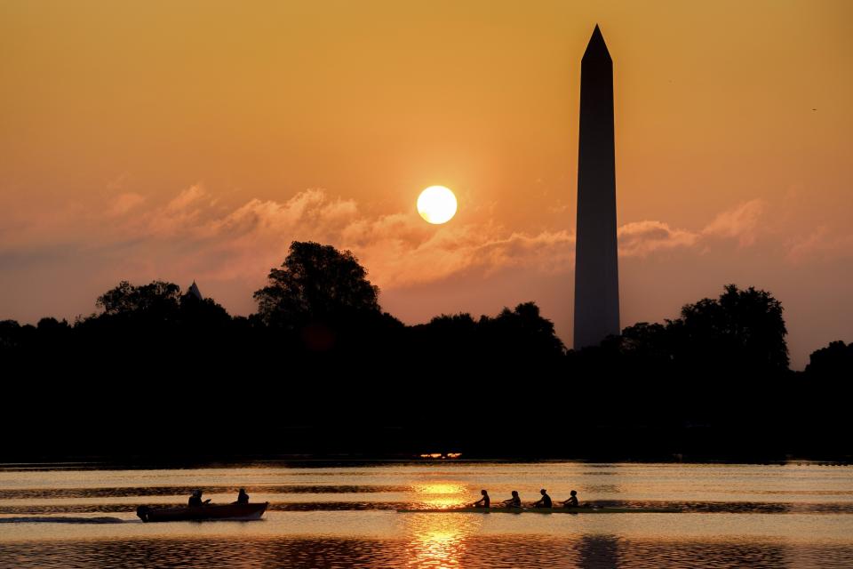 A rowing team glides along the Potomac River past the Washington Monument as the sun rises on another hot and humid day in Washington, Thursday, July 20, 2023. (AP Photo/J. David Ake)