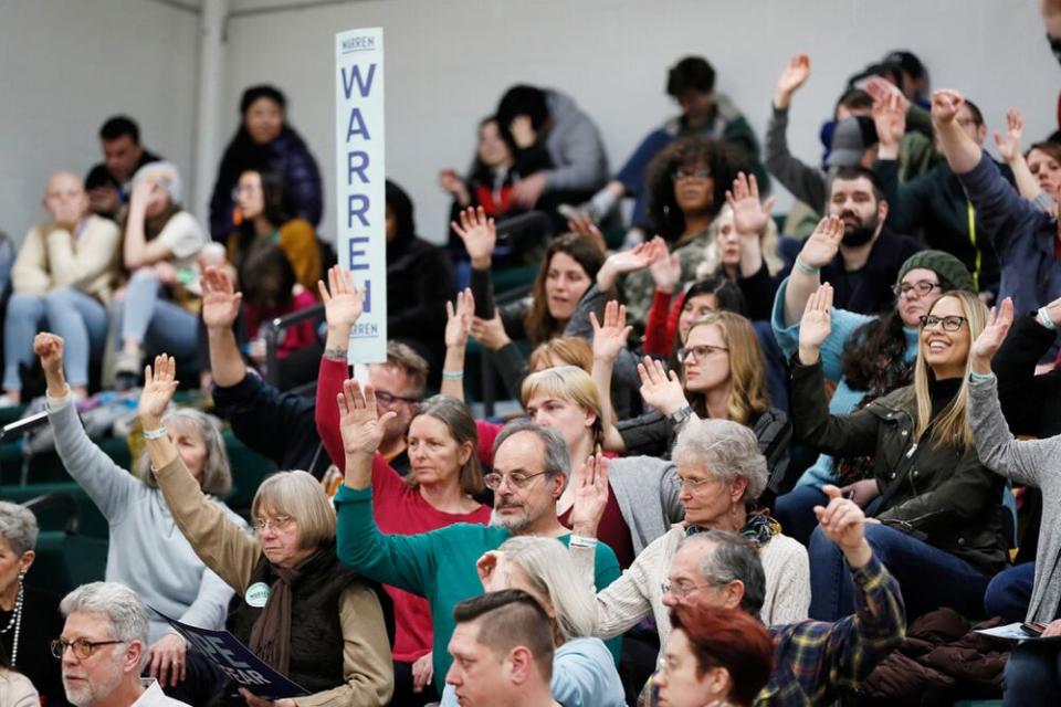 Supporters for Sen. Elizabeth Warren raise their hands to be counted at a caucus site during the Iowa Democratic caucus at Hoover High School, in Des Moines, Iowa, on Monday. | Charlie Neibergall/AP/Shutterstock