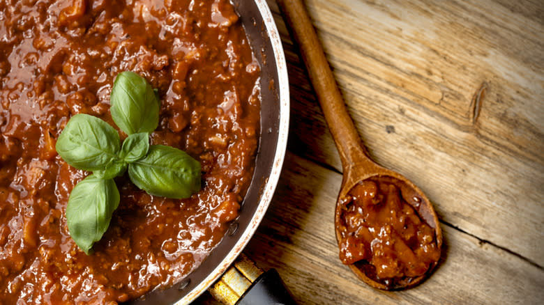 Bolognese sauce in pan and on wooden spoon