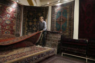 A shopkeeper shows a carpet to a customer at a carpet shop in the old main bazaar of Tehran, Iran, Thursday, June 13, 2024. The rise of the “Hamster Kombat” app in Iran highlights a harsher truth facing the Islamic Republic's economy ahead of its presidential election this week to replace the late President Ebrahim Raisi, who died in a helicopter crash in May. (AP Photo/Vahid Salemi)