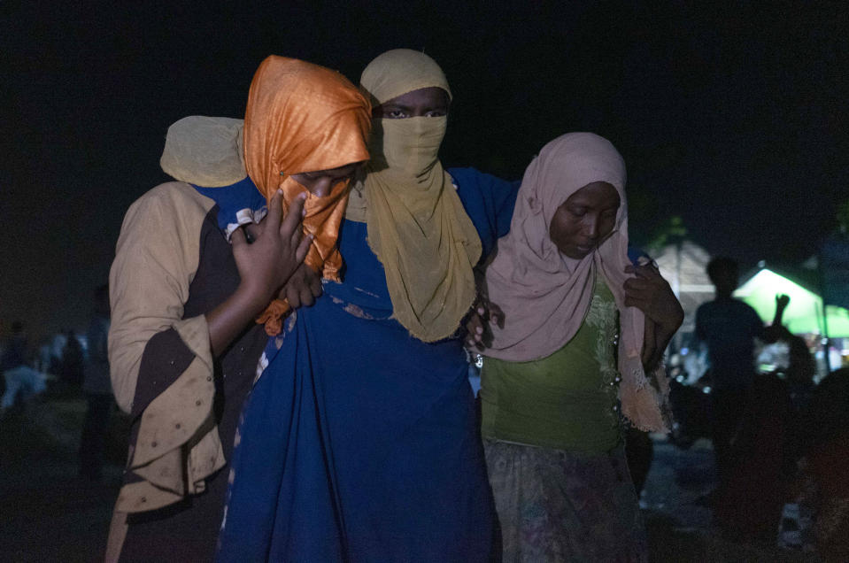 An ethnic Rohingya woman is assisted to walk by others after the boat carrying them landed in Lhokseumawe, Aceh province, Indonesia, early Monday, Sept. 7, 2020. Almost 300 Rohingya Muslims were found on a beach in Indonesia's Aceh province Monday and were evacuated by military, police and Red Cross volunteers, authorities said. (AP Photo/Zik Maulana)