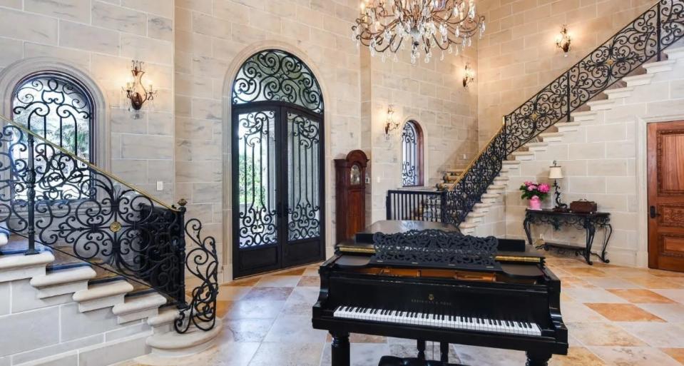 A piano occupies a prominent spot in the stair hall of Billy Joel's Manalapan home near Palm Beach, which has been relisted for sale at $54.9 million, a $10 million drop from its previous price.