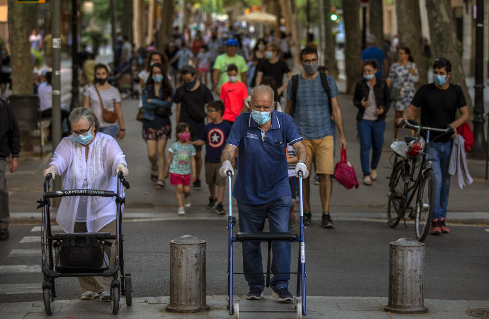 People walk on a street in Barcelona on Monday, May 25, 2020. Roughly half of the population, including residents in the biggest cities of Madrid and Barcelona, are entering phase 1 on Monday, which allows social gatherings in limited numbers, restaurant and bar service with outdoor sitting and some cultural and sports activities. (AP Photo/Emilio Morenatti)