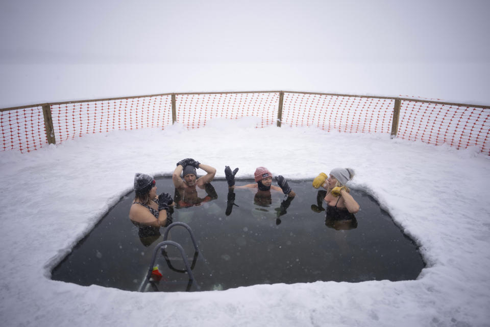 Rachel Banks Kupcho, Matt Nelson, Steve Jewell, and Cindy Murphy, from left, chatted while they soaked in the 33 degree water of Lake Harriet in the snow Wednesday, Feb. 22, 2023, in Minneapolis. (Jeff Wheeler/Star Tribune via AP)