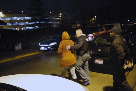 Police officers talk to a woman who identified herself as a family member of the suspects in the fatal shooting of a Prince George's County Police officer, as she looked for the suspects at Prince George's Hospital Center, where the officer was confirmed dead, in Cheverly, Maryland March 13, 2016. REUTERS/Jonathan Ernst