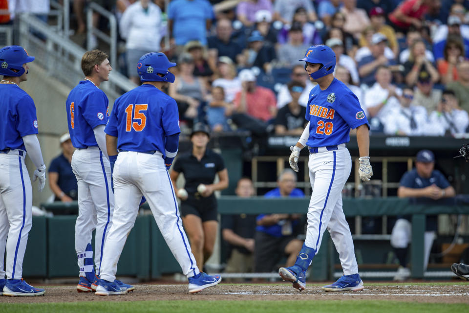 Florida's Luke Heyman (28) scores on a two-run home run in the fourth inning against Oral Roberts in a baseball game at the NCAA College World Series in Omaha, Neb., Sunday, June 18, 2023. (AP Photo/John Peterson)
