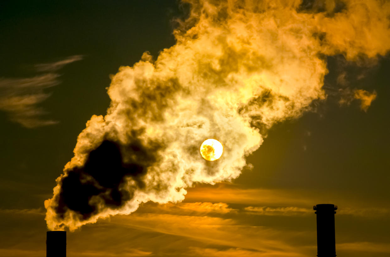 The sun shines through the exhaust gases of a power plant