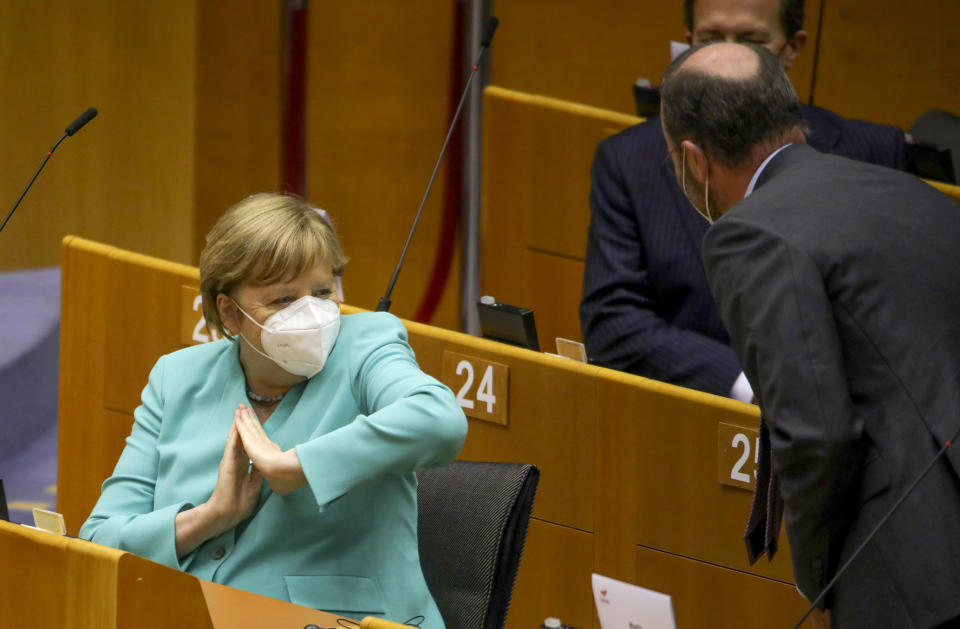 German Chancellor Angela Merkel, left, offers an elbow to gesture hello as she attends a plenary session at the European Parliament in Brussels, Wednesday, July 8, 2020. Germany has just taken over the European Union's rotating presidency, and must chaperone the 27-nation bloc through a period of deep crisis for the next six months and try to limit the economic damage inflicted by the coronavirus. (AP Photo/Olivier Matthys)