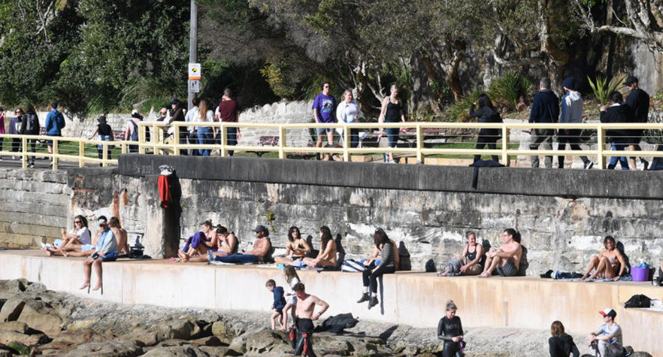 People sit on a wall at the south end of Manly beach over the weekend. Source: Getty