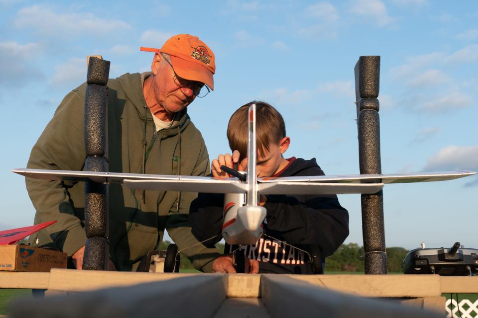 Greg Inkmann, president of the Foundation for Aeronautical Education, helps 9-year-old Liam Robbins straighten the nose wheel on his AeroScout after a flight May 15. Inkmann says learning the mechanics of rc planes is just as important as flying them.