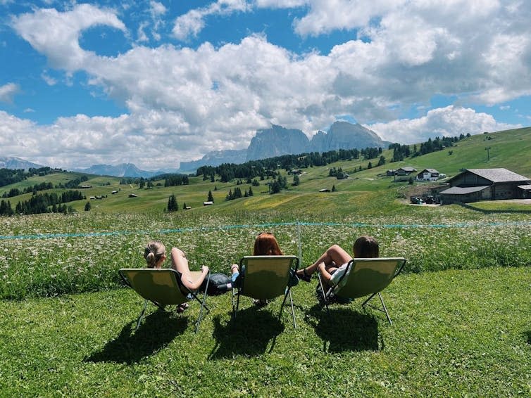 Three girls sat in chairs on a field