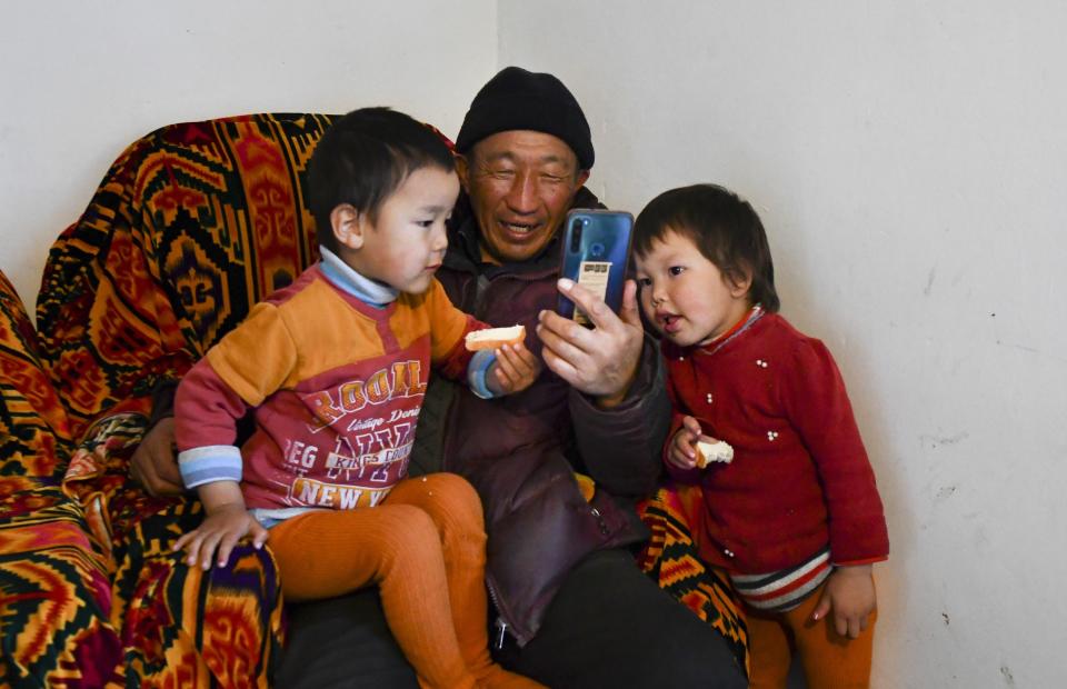 Kanat Kaliyev and his grandchildren Aruke, right, and Baisal talk with their relatives on Skype at their family house in the village of Tash-Bashat about 24 kilometers (15 miles) southeast of Bishkek, Kyrgyzstan, Tuesday, Oct. 20, 2020. The political turmoil that has gripped Kyrgyzstan hasn’t reached this quiet village in the mountains near the capital, where residents talk about the country’s feuding elites with resignation and disdain. (AP Photo/Vladimir Voronin)