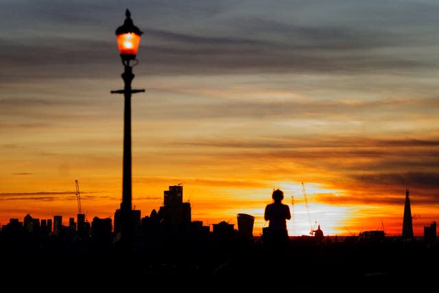 A woman takes a photograph of the sunrise from Primrose Hill in west London