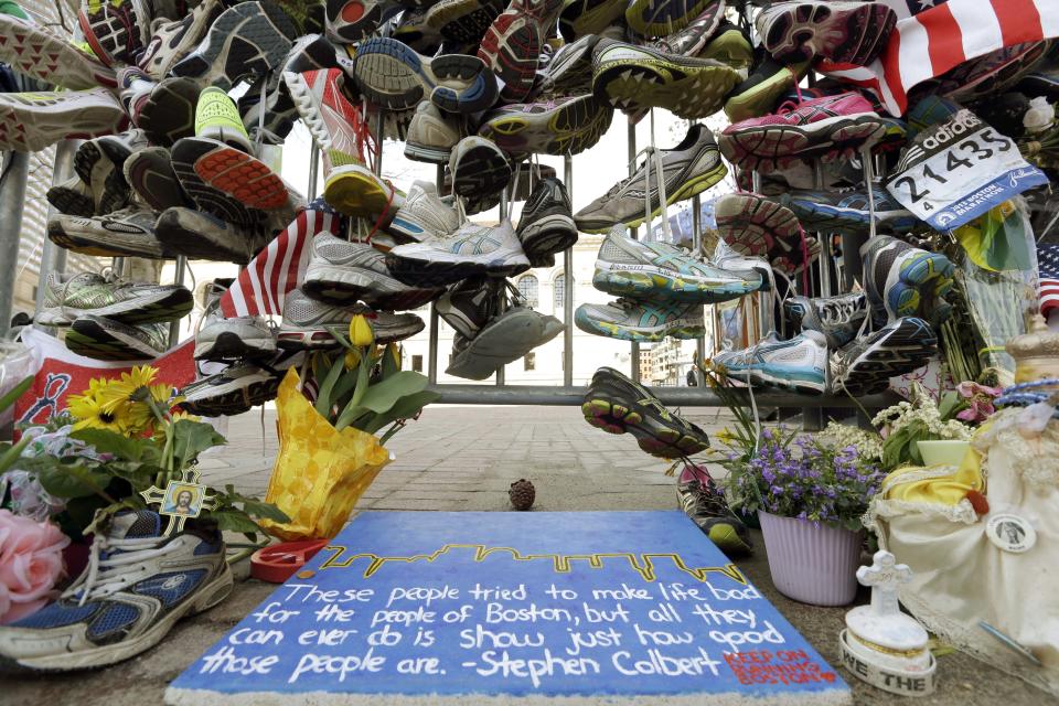 In this April 25, 2013 photo, running shoes and other items adorn a makeshift memorial near the Boston Marathon finish line in Boston's Copley Square. Thousands of items from the original memorial for marathon bombing victims are going on display at the Boston Public Library in April 2014 to mark the anniversary of the attacks. (AP Photo/Elise Amendola)