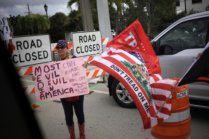 A supporter of President Trump displays a sign as the presidential motorcade passes through West Palm Beach