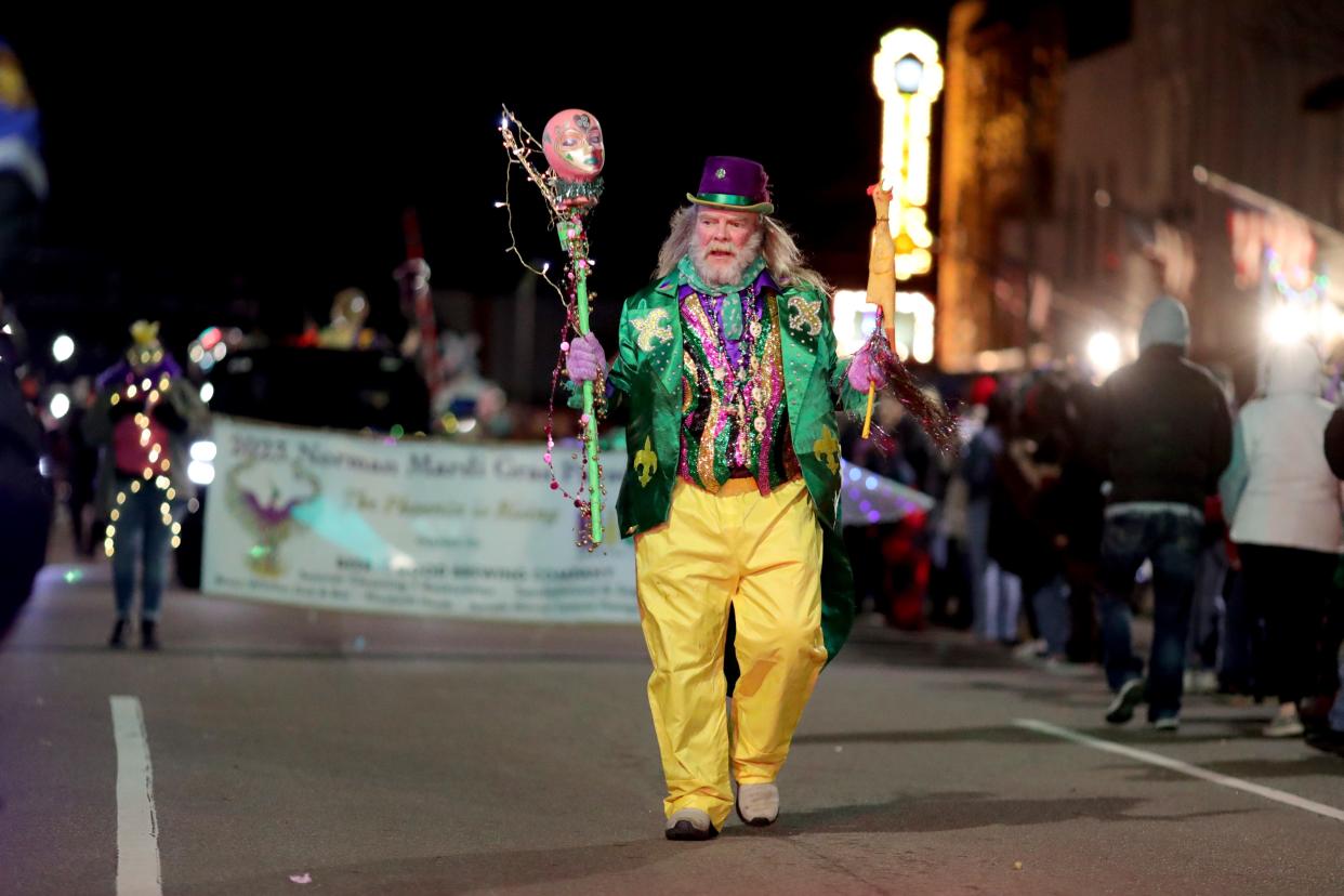 A parade participant walks during a 2023 Mardi Gras parade in Norman.