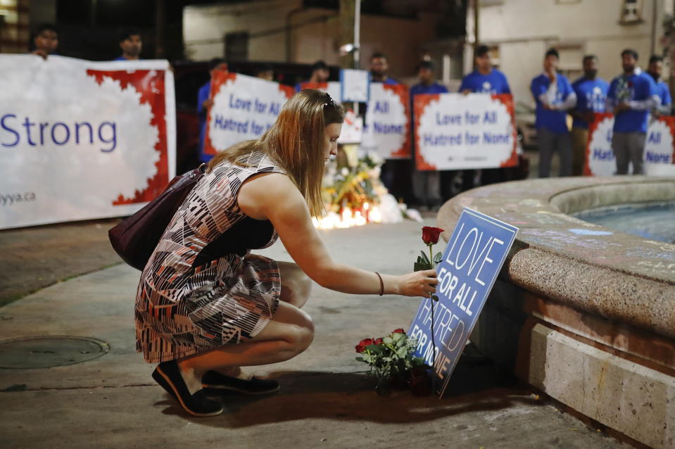 A woman places a flower at a vigil in remembrance of the victims of a shooting the evening before, in Toronto, Monday, July 23, 2018. (Mark Blinch/The Canadian Press via AP)