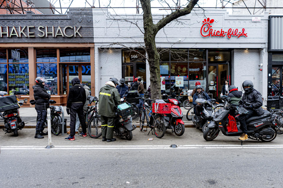 Delivery workers wait in front of restaurants for orders, Thursday, Feb. 1, 2024, in New York. A wage law in New York City meant to protect food delivery workers is getting backlash from app companies like Uber, GrubHub and DoorDash, who have cut worker hours and made it more difficult to tip. (AP Photo/Peter K. Afriyie)