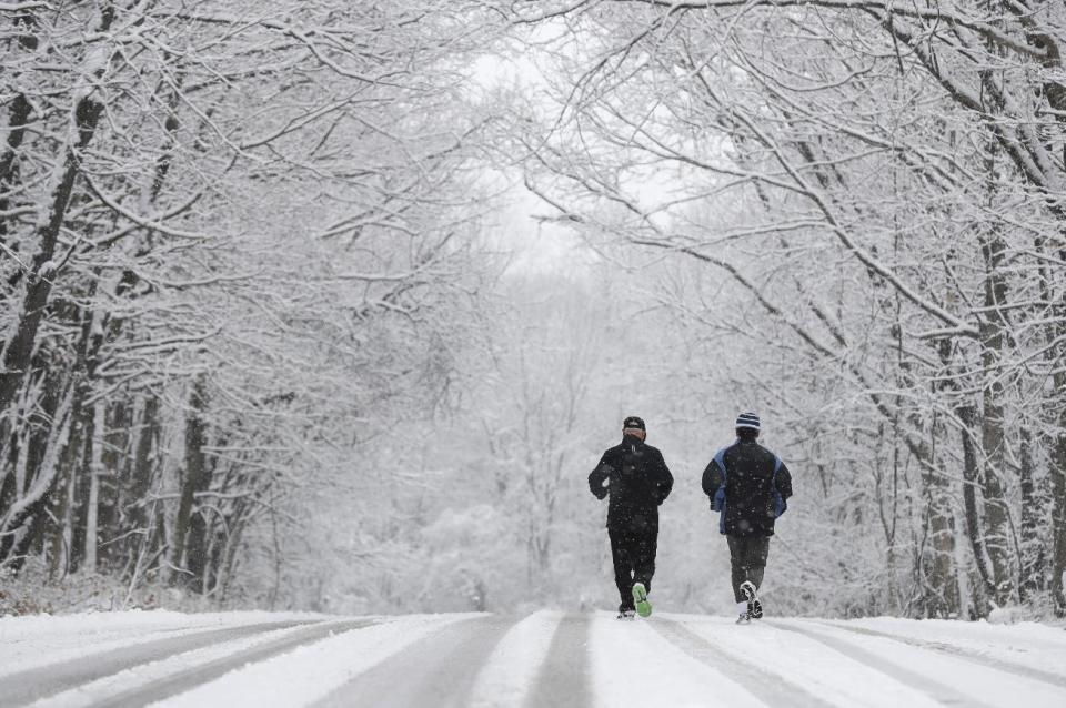 Ken Perry and Stan Ly go for a run in Eagle Creek Park as snow falls Tuesday, Dec. 13, 2016, in Indianapolis. (AP Photo/Darron Cummings)