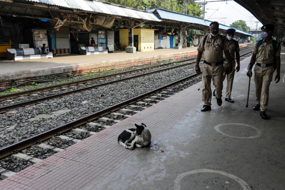 Railway Protection Force personnel patrol a deserted local railway platform as local trains were suspended due to the coronavirus pandemic, in Kolkata, India, Saturday, Oct. 10, 2020. India's total coronavirus positive cases near 7 million with another 73,272 infections reported in the past 24 hours. The Health Ministry on Saturday put the total positive caseload at 6.97 million, second to 7.66 million infections registered in the worst-hit United States. (AP Photo/Bikas Das)