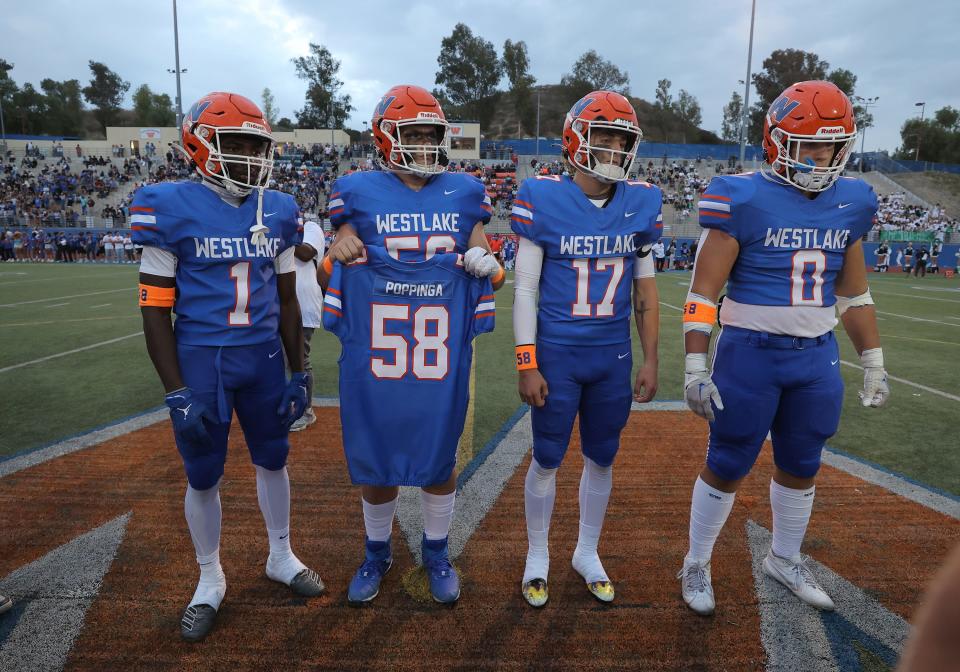 Westlake High's Ife Orekoya, Jayson Brattin, Tagg Harrison and Lawson Grace hold the uniform jersey of Julius Poppinga during the coin toss before the start on the Warriors' home game against Thousand Oaks on Sept. 1.