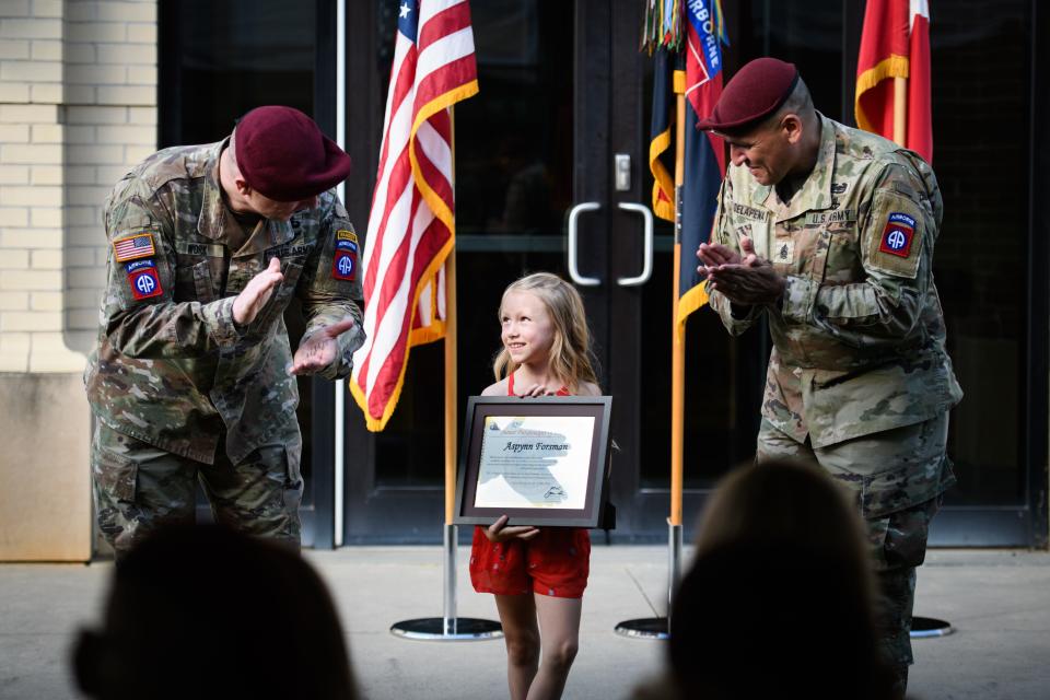 Maj. Gen. Pat Work, left, and Command Sgt.  Maj. Randolph Delapena, right, congratulates 82nd Airborne Division Junior Paratrooper of Year Aspynn Forsman at Fort Liberty on Tuesday, May 21, 2024.