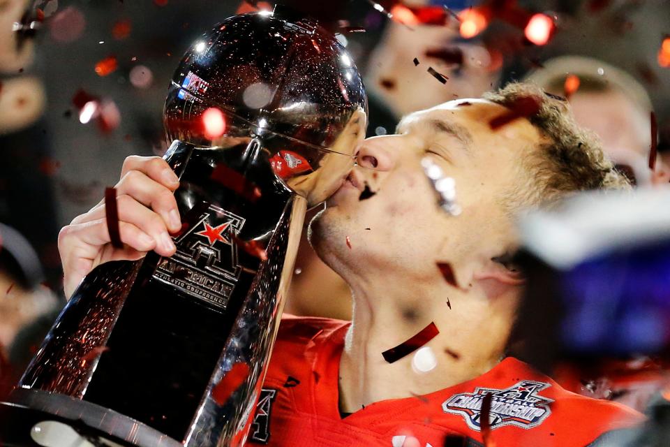 Cincinnati Bearcats senior quarterback Desmond Ridder kisses the American Athletic Conference championship trophy. A Louisville native, Ridder is the nation's winningest college quarterback with a career record of 41-5.