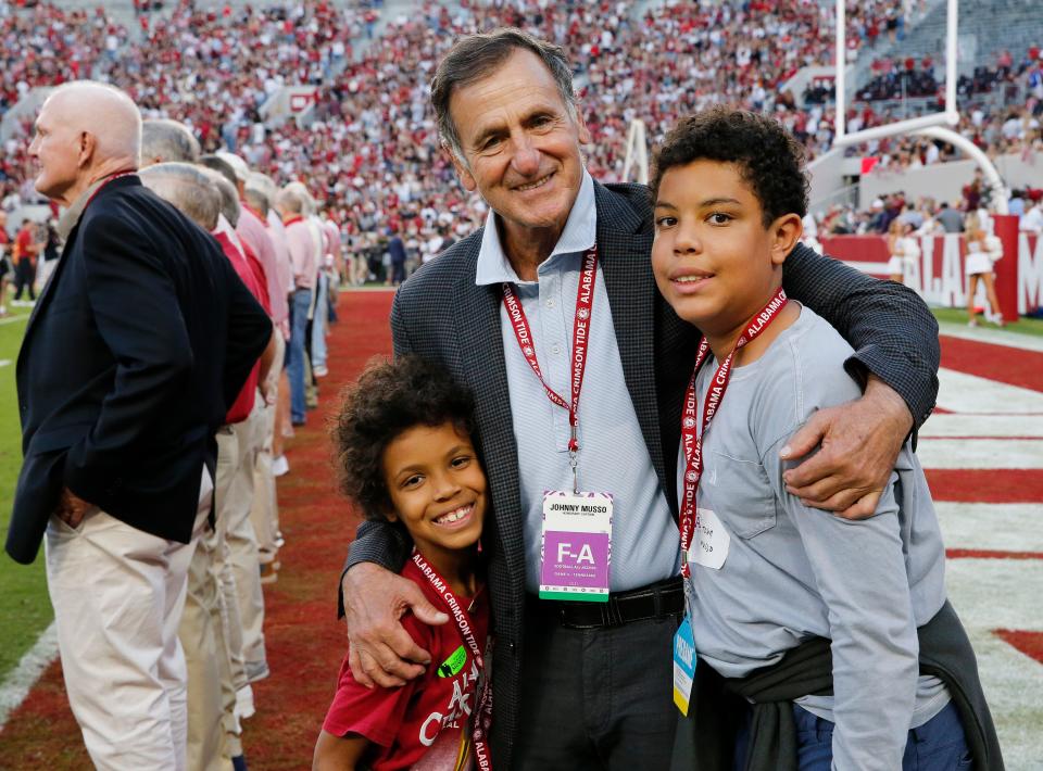 Oct 23, 2021; Tuscaloosa, Alabama, USA;  Crimson Tide legend Johnny Musso embraces his grandsons Chase Jusso and John David Musso as they pose for a photo on the field before Alabama's game with Tennessee at Bryant-Denny Stadium. Musso was an honorary captain for the game. Mandatory Credit: Gary Cosby Jr.-USA TODAY Sports